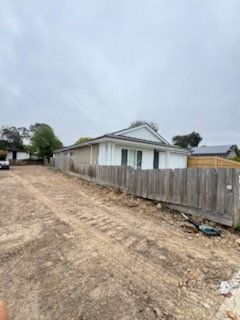 Old grey paling fence beside a new home
