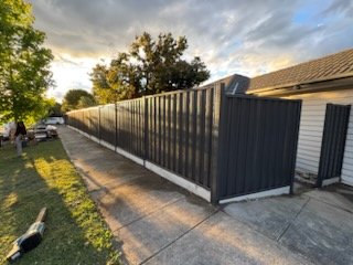 Grey Colorbond front and side fence along a footpath at sunset
