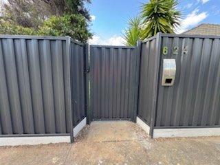 Grey Colorbond front fence with a matching gate and letterbox