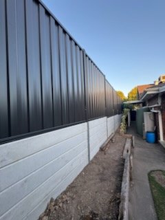 Dark Colorbond side fence on concrete plinths beside a path