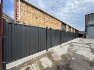Dark Colorbond fence along a warehouse lane