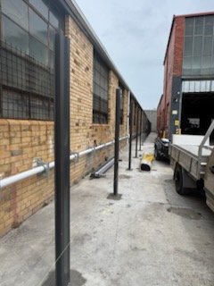 Steel posts concreted in along a warehouse laneway